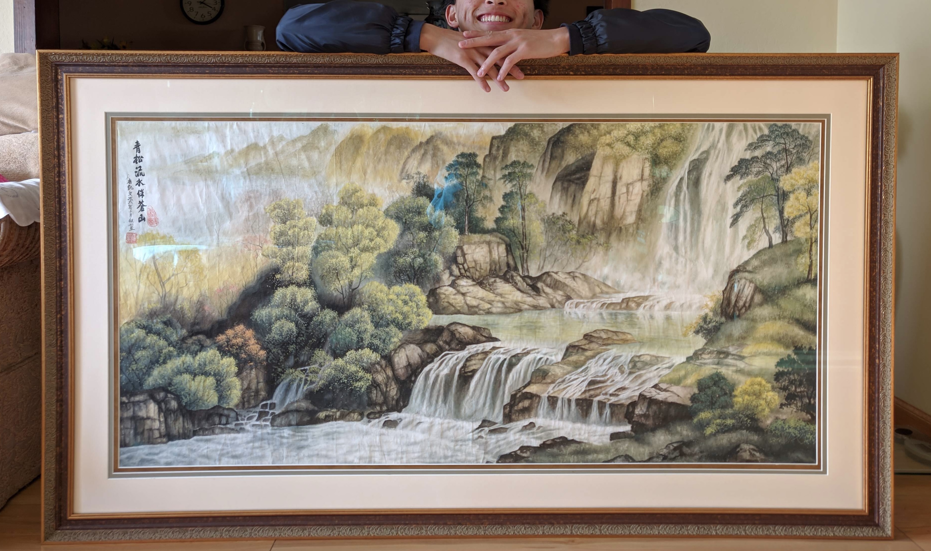 Kaiwen posing behind a framed traditional Chinese watercolor painting.