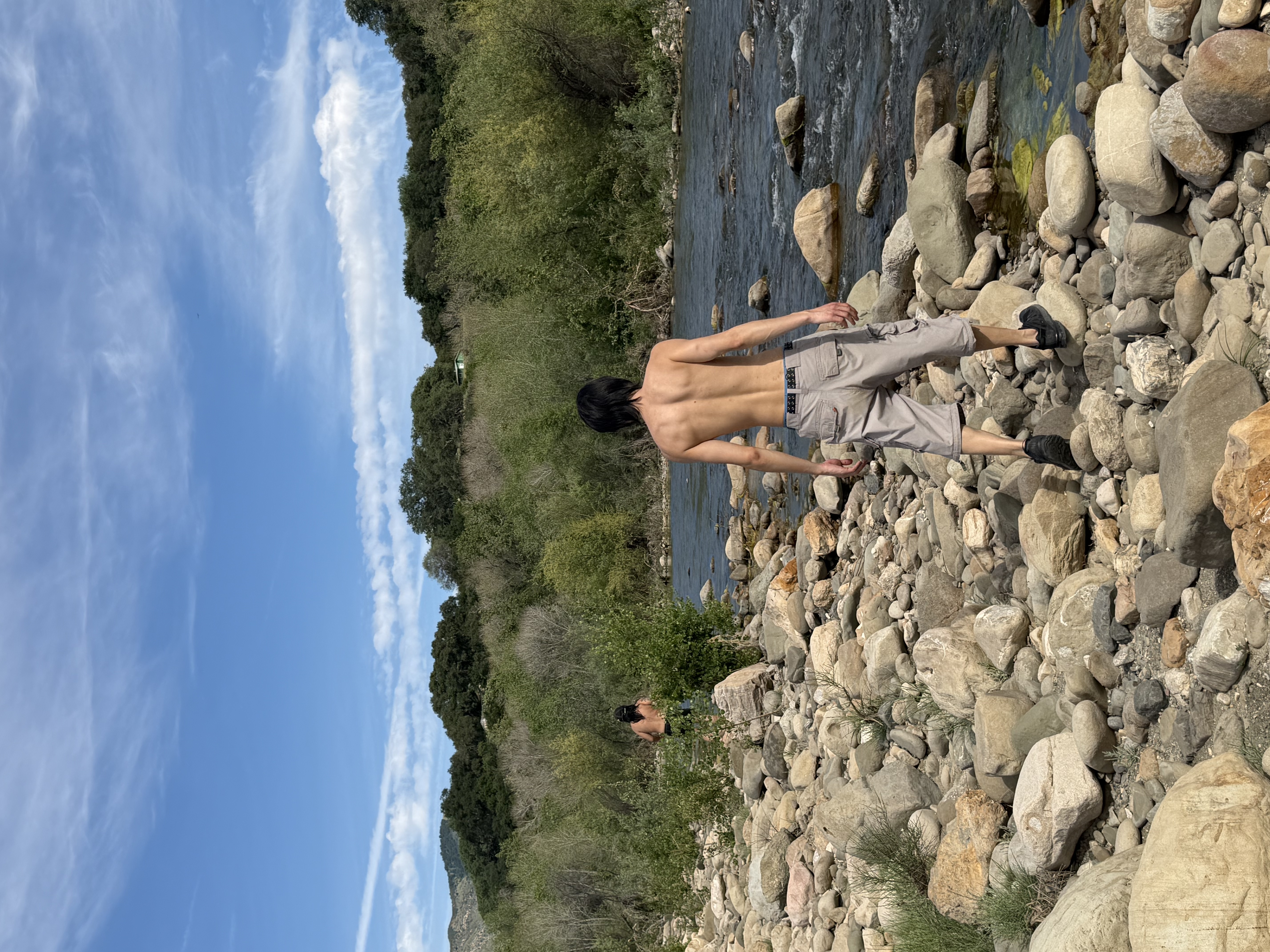 Kaiwen walking along a rocky riverbed.